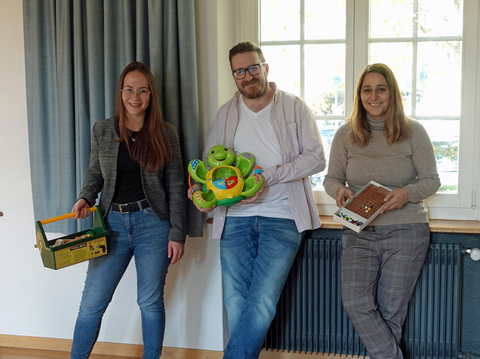 Anna Renner, Christoph Hrmann und Nadia Pellegrino Colantoni halten je ein Spielzeug in der Hand.