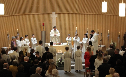 Erstkommunionkinder mit Priester um Altar